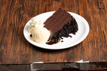 Tarta de chocolate  con helado de vainilla  sobre mesa de madera. Chocolate cake with vanilla ice cream on wooden table.