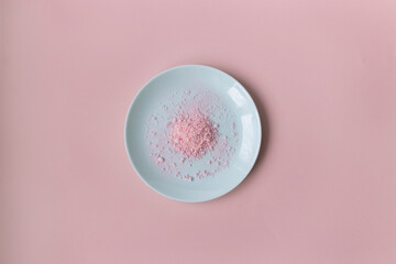 Top view of powder of pink meringue on the light blue plate