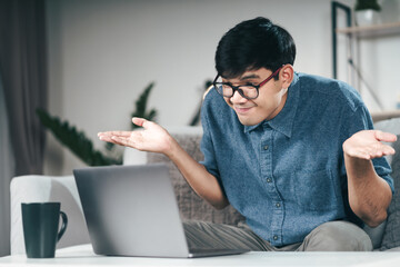 Confused clueless man using laptop computer for Video conference call shrugging shoulders making no idea, whatever gesture I don't know, who cares Concept.