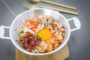 Fried Egg Breakfast with toppings, sausages, crab sticks, Vietnamese sausage, bacon, and vegetables Thai food on a wooden cutting board and cutlery copy space Top View.