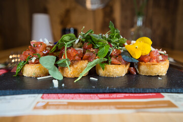 Bruschetta mit Blüte und Wildkräuter auf einem schwarzen Steinteller