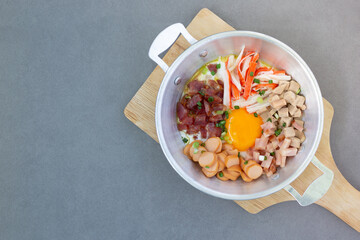 Fried Egg Breakfast with toppings, sausages, crab sticks, Vietnamese sausage, bacon, and vegetables Thai food on a wooden cutting board and cutlery copy space Top View.