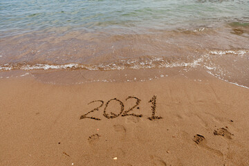 inscription on the sand 2021. symbol 2021 on the coast, overlooking the sea. Summer holidays in the new season.