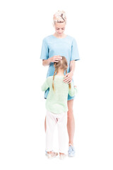 Vertical full length isolated shot of cute little girl with two braids hugging her loving mother, white background