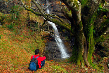 A hiker observes the Uguna waterfall. Gorbeia Natural Park. Basque Country. Spain