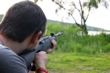 A young guy is preparing to shoot from a pneumatic weapon.