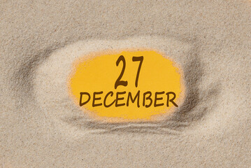 December 27. 27th day of the month, calendar date. Hole in sand. Yellow background is visible through hole. Winter month, day of the year concept