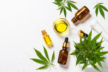 Cannabis oil hemp oil in glass bottles and cannabis leaves at white table. Flat lay image with copy...