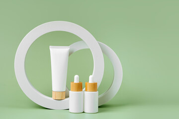 Cream tube and dropper mockup with  geometrical forms on green background. Natural skincare beauty product for branding and packaging presentation.