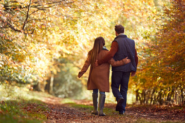 Fototapeta premium Rear View Of Loving Mature Couple Walking Along Track In Autumn Countryside