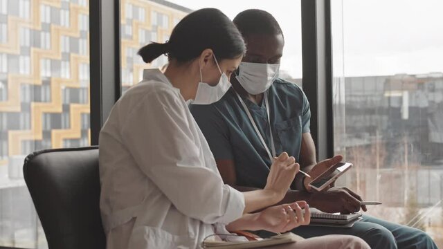 Medium slowmo of two young multiethnic doctors looking at radiograph image on tablet display consulting about diagnosis