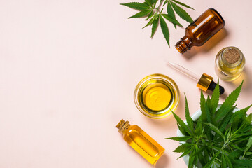 Cannabis oil hemp oil in glass bowl and cosmetic bottles with dropper and fresh leaves at pastel background. Flat lay image with copy space.