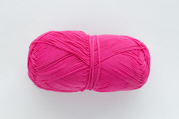 One oblong ball of bright pink or purple color in the center of the frame on a white woven background on the theme of handmade hobby knitting