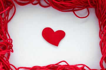 Naklejka premium Frame around the edges of the frame made of red thread with a heart in the middle for knitting handmade and hobby on a white background from fabric copy space 14 february valentine's day