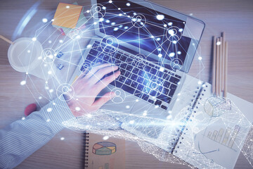 Double exposure of man's hands typing over computer keyboard and social network theme hologram drawing. Top view. People connection web concept.
