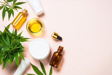 Cannabis cosmetic products. Cannabis oil, cream, soap and fresh leaves at pastel background. Flat lay with copy space.