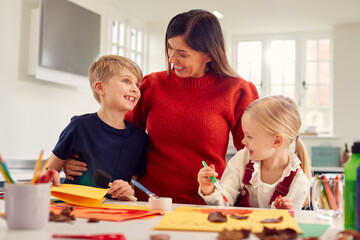 Mother With Children At Home Doing Craft And Making Picture From Leaves In Kitchen