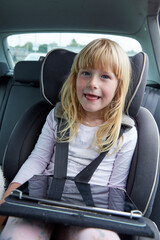 Child with tablet looking at camera inside car