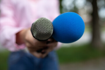 Journalist at news conference, writing notes, holding microphones