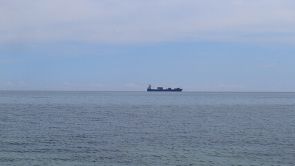 A large merchant ship sails on the horizon of the Black Sea.
