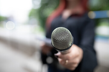 Journalist at news conference, writing notes, holding microphones