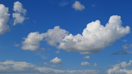 Blue sky with beautiful whimsical clouds hovering low above the ground.