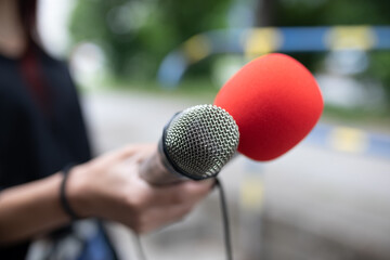 Journalist at news conference, writing notes, holding microphones