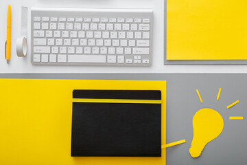 Yellow light bulb idea metaphor on desktop with keyboard pc computer and suppliers in workspace on...