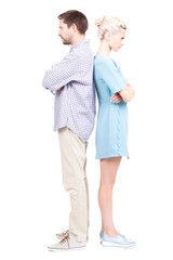 Vertical full length studio shot of modern Caucasian man and woman standing back to back with arms crossed angry at each other