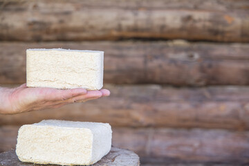 The fuel briquette lies in the palm of a person.