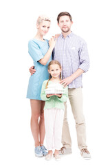 Fototapeta na wymiar Vertical full length shot of modern family with little daughter standing together, girl holding house model looking at camera, white background