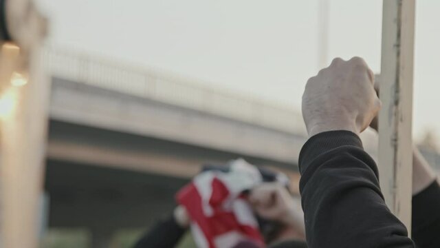 Slowmo shot of unrecognizable people chanting and protesting with raised fists, signs and USA flag