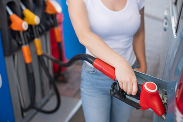 Caucasian woman refueling a car at a self-service gas station.