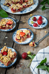 Strawberry and rhubarb meringue crumble squares on white and blue plates on wooden table.