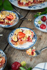 Strawberry and rhubarb meringue crumble squares on white and blue plates on wooden table.