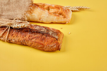 Top view of two baguette bread on a yellow surface.  Concept of homemade bread, small bakery, natural farm products, local food,  domestic production. Healthy and tasty organic food. Copy space.