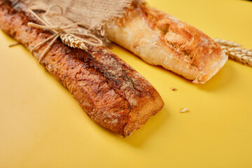 Top view of two baguette bread on a yellow surface.  Concept of homemade bread, small bakery, natural farm products, local food,  domestic production. Healthy and tasty organic food. Copy space.