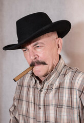 The cowboy with mustache, in a black hat smoking a cigar