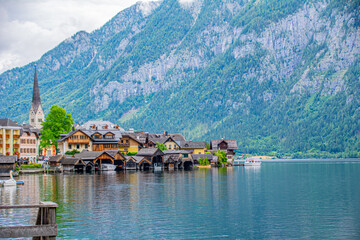 Fototapeta premium Historic Halstatt town with lake and Alps mountain at the background in Austria on a rainy summer day with overcast weather
