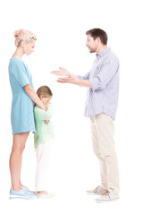 Vertical full length side view studio shot of husband and wife having conflict quarrelling, their daughter feeling sad about it, white background