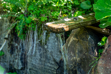 Drinking water fountain made of wood with fresh spring water in a forest in the Salzburg Alps in Austria