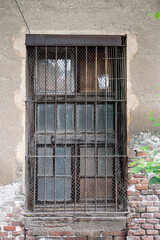 Detail of an old window with a rusty grill, it is an abandoned house