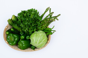 Top view of a basket with variety of green seasonal vegetables, raw food concept.