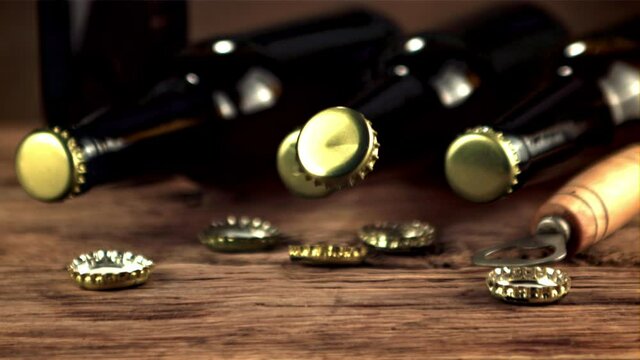 Super slow motion lids from beer bottles fall on the table. On a wooden background.Filmed on a high-speed camera at 1000 fps.