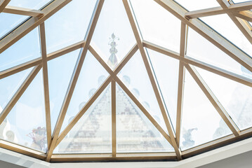 Stylish glass ceiling made of triangle pieces and golden frame in hall of theater on sunny spring day closeup low angle shot