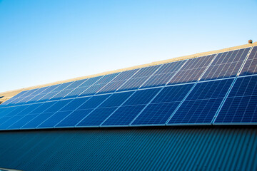 Wide shot of two rows of solar panels on a roof.  Half of the panels are covers in shade and the...