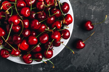 Naklejka na ściany i meble Cherry. Sweet Cherries in bowl on dark stone concrete background. Ripe Sweet Red Cherries.