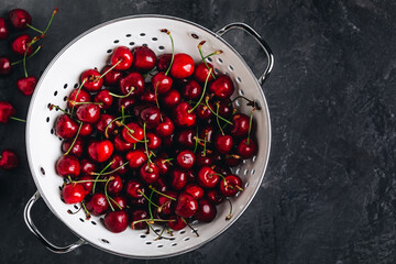 Cherry. Sweet Cherries in white colander on dark stone concrete background. Ripe Sweet Red Cherries.