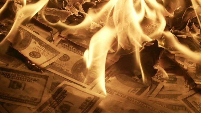 many Hundred dollar bills scattered on the floor are burned, close-up. Lot of hundreddollar bills are burning on the floor. Concept of inflation
