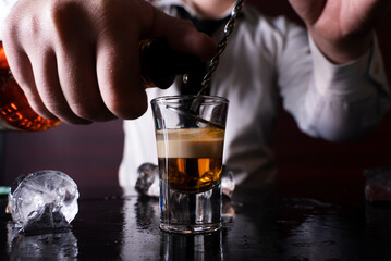 Barman preparing cocktail shots at the bar counter. Barman mixing drinks at the night club..